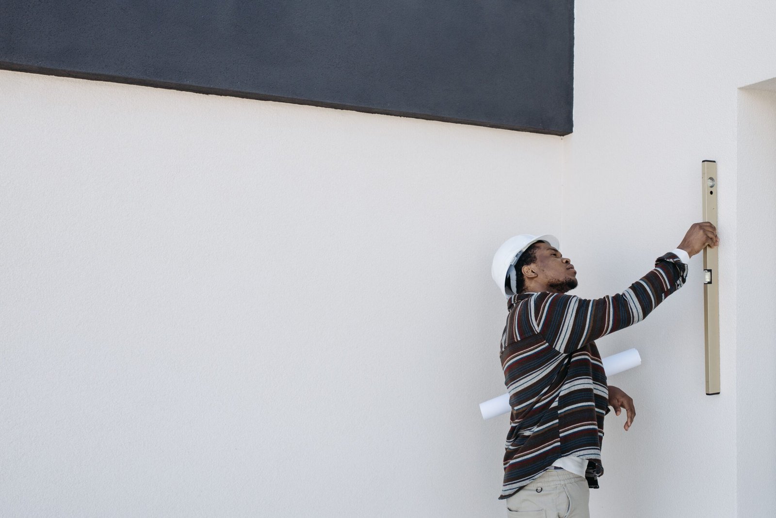 Engineer in hard hat checking wall alignment with a level tool