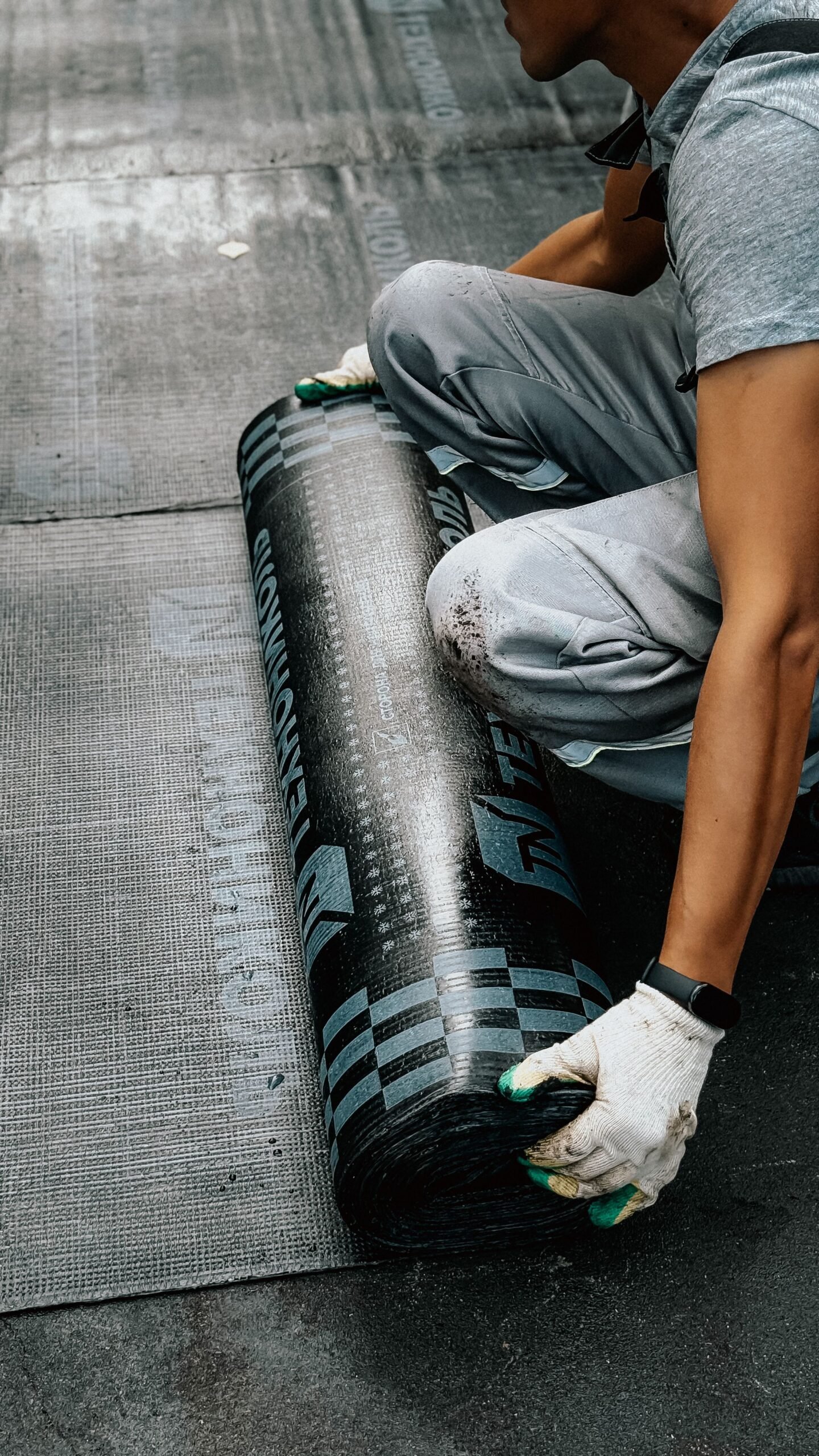 Worker installing a waterproofing membrane on a roof